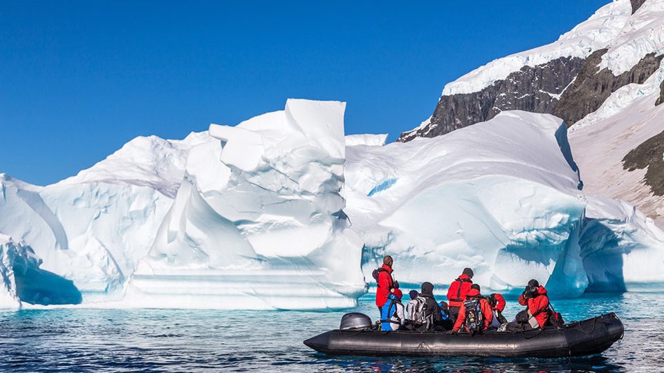 A group of men looking at a huge block of iceberg